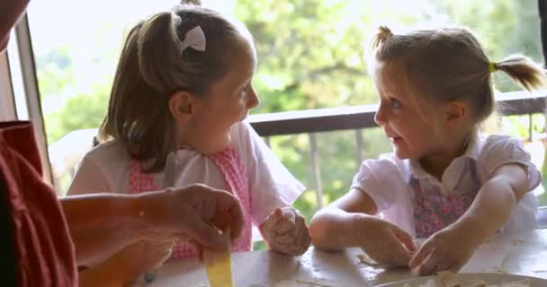 Primer plano de dos chicas cocinando pasta con la abuela. Momento divertido de dos niños aprendiendo a hacer pasta con la abuela. — Vídeos de Stock