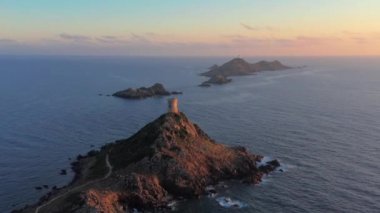 Deniz batımında, Dağ Kayalık Tepesi 'ndeki hava manzaralı deniz feneri. Gün doğumunun inanılmaz görüntüleri. Renkli günbatımında, kayalık adada, gün batımında kayalık deniz fenerinde.