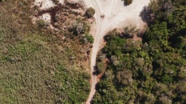 Beyaz sahil kumsalı, turkuaz ve mavi deniz, çevredeki deniz orman bitkileri, kızıl kayalar, güneşli bir yaz gününde dalgalar. Deniz arka planı, el değmemiş manzara.