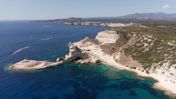 Veduta aerea della spiaggia di scogliera bianca sulla baia sulla costa con onde nel mare blu. Riprese aeree dell'immensa scogliera bianca sul mare turchese con barca vicino a Bonifacio Corsica — Video Stock