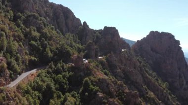 Kayalık kızıl dağın panoramik hava manzarası, güneşli bir yaz gününde arka planda deniz bulunan kanyon. Karakteristik kaya dağları, mavi deniz, mavi gökyüzü, güneşli gün. Korsika Kalkanları.