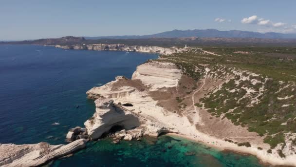 Kıyı şeridindeki beyaz kayalık sahili ve mavi denizde dalgalar. Bonifacio Korsika yakınlarında teknesiyle turkuaz denizde uçsuz bucaksız bir uçurum görüntüsü. — Stok video