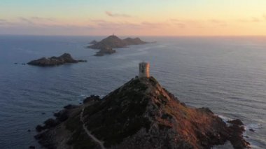 Deniz batımında, Dağ Kayalık Tepesi 'ndeki hava manzaralı deniz feneri. Gün doğumunun inanılmaz görüntüleri. Renkli günbatımında, kayalık adada, gün batımında kayalık deniz fenerinde.