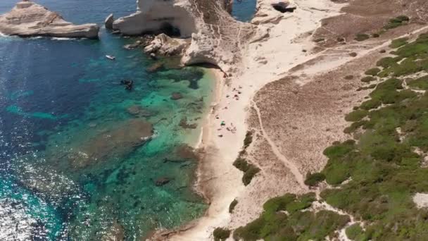 Kıyı şeridindeki beyaz kayalık sahili ve mavi denizde dalgalar. Bonifacio Korsika yakınlarında teknesiyle turkuaz denizde uçsuz bucaksız bir uçurum görüntüsü. — Stok video