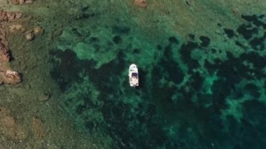 Aerial top view of white boat floating in the middle of blue sea, waves,and red rocks. abstract sea green shades coral reef background with boat. Tropical coral reef turquoise water texture. 