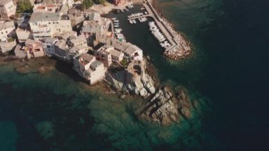 Korsika 'daki karakteristik taş köy limanının havadan görünüşü. Canlı mavi deniz. Kıyı manzarası, güzel deniz, evler, ağaçlar güneşli bir yaz gününde.. 