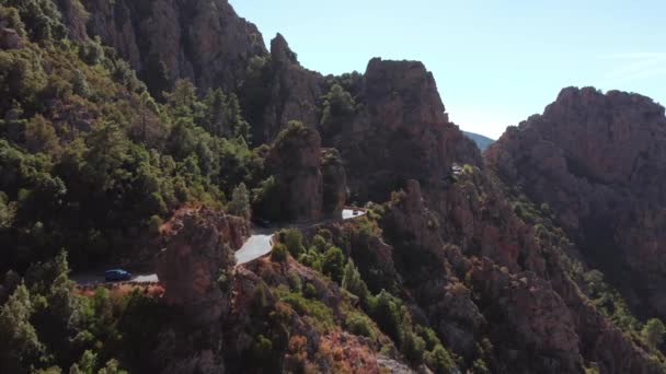 Panoramisch uitzicht op de rotsachtige rode berg, canyon met elektrische auto rijden in een gebogen weg in een zomer zonnige dag. Karakteristieke rotsbergen, blauwe lucht, zonnige dag.Corsica Calanques. — Stockvideo