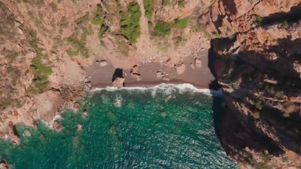 Flygfoto över den röda sandstranden, vågor som krossar stranden. Färgat hav, blå turkos, höga röda klippor på båda sidor, gröna buskar av vegetation. — Stockvideo