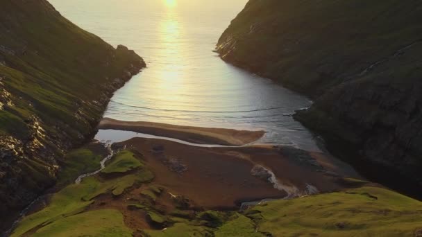 Vista aérea superior do pôr do sol na praia com incrível sol reflexo dourado em ondas calmas. Praia dourada e silhueta de montanha em ambos os lados. gaivota voando, Ilhas Faroé — Vídeo de Stock