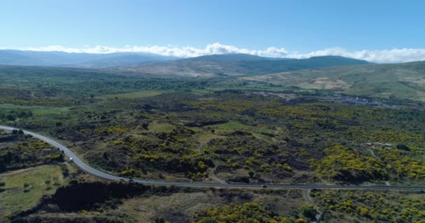 Aerial view of beautiful landscape in Sicily. A curved road cross the valley. Green trees and bushes cover the land all around in a summer day. Mountain, blue sky and clouds in the background — стоковое видео