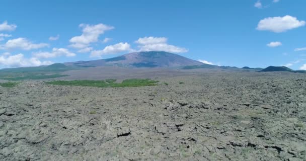 Spectaculaire drone antenne onthullen van actieve vulkaan Etna in het prachtige eiland Sicilië. Wolken bedekken de top van de vulkaan. Blauwe lucht rondom. Slechts een paar struiken in het droge en droge land. — Stockvideo
