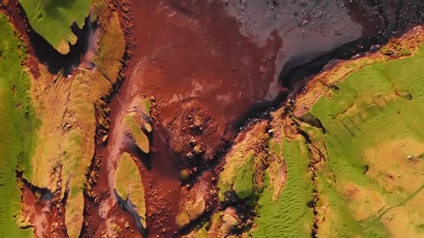 Luftaufnahme des roten Strandes auf den Färöern, Drohne umrahmt grünes flaches Land und bewegt sich während des sommerlichen Sonnenuntergangs zum felsigen roten Strand. — Stockvideo