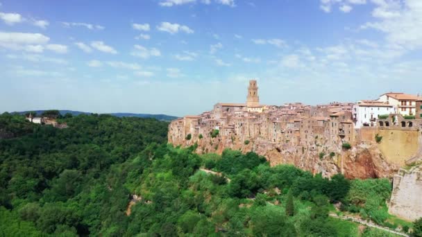 Letecký pohled na středověké město Pitigliano, Toskánsko ve dne. Středověká architektura horského kopce, křivolaká cesta borovým lesem. Slunce svítí skrz domy — Stock video