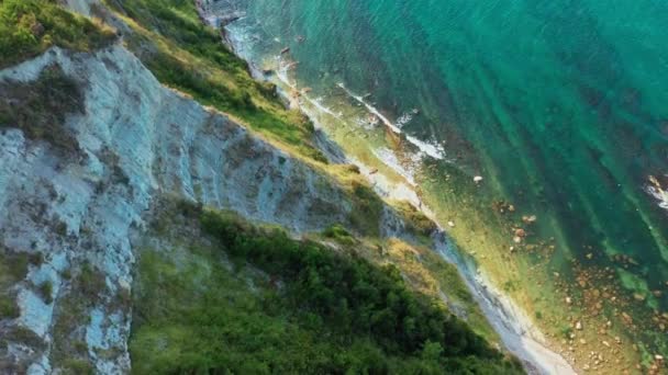 Luftaufnahme der felsigen Küste, blaues Meer, tiefe weiße Klippen. Weiße Felsen, Bäume. Meereswellen im blauen Meer im Hintergrund, blauer Himmel an einem Sommertag in Conero, Italien — Stockvideo