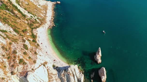 Vista superior de la playa blanca, acantilados rocosos, mar azul, acantilados blancos profundos. Rocas blancas, árboles. Olas marinas en la costa azul, bahía rocosa blanca, en un prístino ecosistema cielo azul en un día de verano en Conero, Italia — Vídeos de Stock