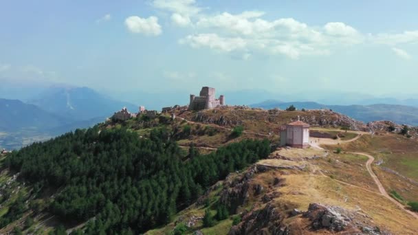 Vue aérienne de l'ancien château sur la colline de montagne, forêt de pins sur la pente de montagne.Rochers blancs et route sale incurvée le long de la montagne. Chaîne de montagnes en arrière-plan avec ciel bleu un jour ensoleillé d'été — Video