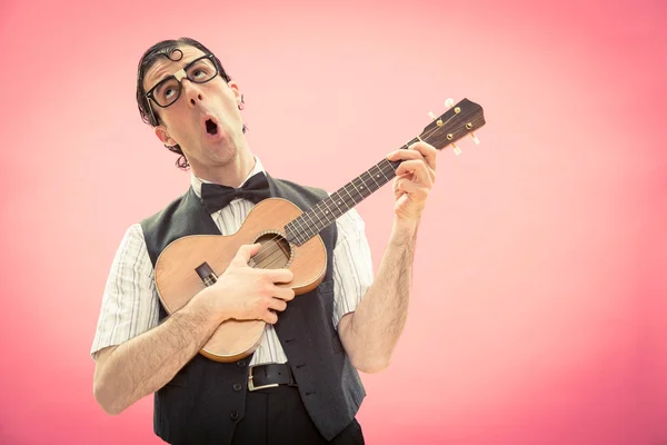 Nerd man with glasses play music with ukulele guitar