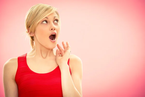 Young beautiful woman in red dress surprised on pink — Stock Photo, Image