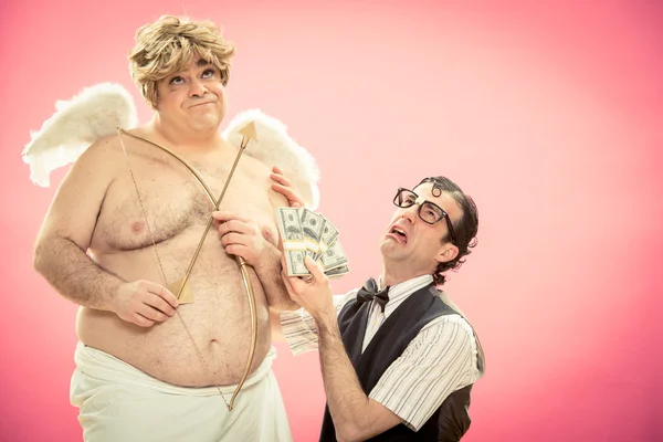 Hombre nerd desesperado con gafas trato de amor arco y flecha con el dinero de Cupido para el día de San Valentín —  Fotos de Stock