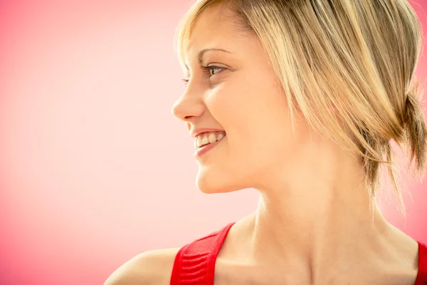 Jonge mooie vrouw in rode jurk tevreden glimlach op roze — Stockfoto