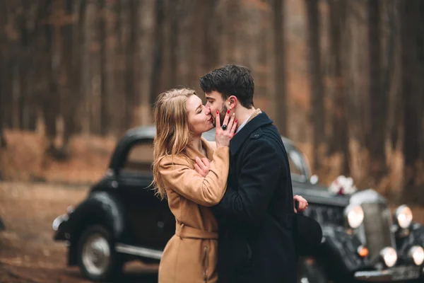 Élégant amour couple de mariage embrasser et embrasser dans une forêt de pins près de voiture rétro — Photo
