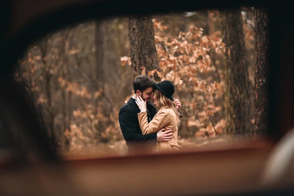 Gorgeous newlywed bride and groom posing in pine forest near retro car in their wedding day — Stock Photo, Image