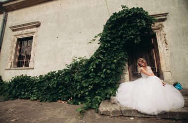 Güzel genç sarışın gelin gelin buketi muhteşem bitkiler altında merdivenlerde oturan ile