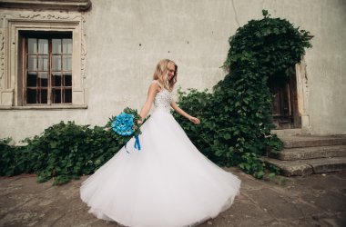 Güzel genç sarışın gelin gelin buketi muhteşem bitkiler altında merdivenlerde oturan ile