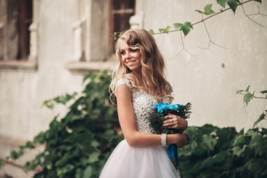 Güzel genç sarışın gelin gelin buketi muhteşem bitkiler altında merdivenlerde oturan ile