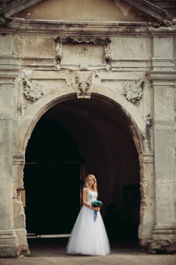 Güzel genç sarışın gelin gelin buketi muhteşem bitkiler altında merdivenlerde oturan ile