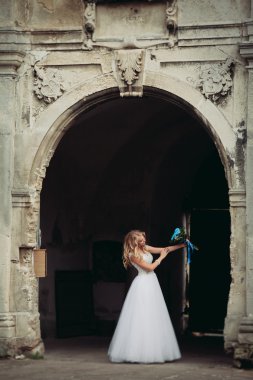 Güzel genç sarışın gelin gelin buketi muhteşem bitkiler altında merdivenlerde oturan ile