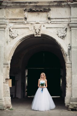 Güzel genç sarışın gelin gelin buketi muhteşem bitkiler altında merdivenlerde oturan ile