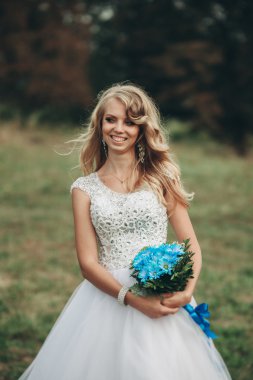 Güzel genç sarışın gelin gelin buketi muhteşem bitkiler altında merdivenlerde oturan ile