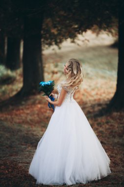 Güzel genç sarışın gelin gelin buketi muhteşem bitkiler altında merdivenlerde oturan ile