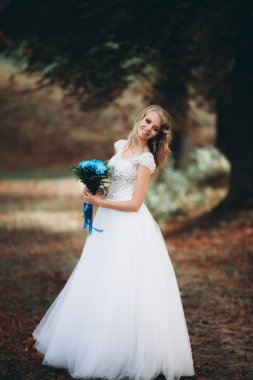 Güzel genç sarışın gelin gelin buketi muhteşem bitkiler altında merdivenlerde oturan ile