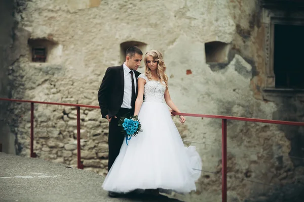 Feliz boda pareja abrazándose y sonriendo el uno al otro en el fondo viejo castillo —  Fotos de Stock