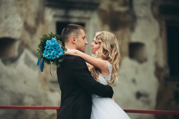 Glückliches Hochzeitspaar umarmt und lächelt sich auf alter Burg an — Stockfoto