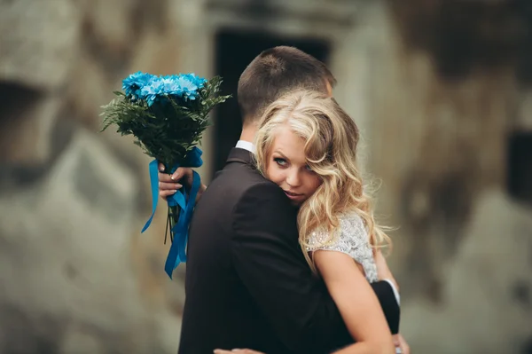 Feliz boda pareja abrazándose y sonriendo el uno al otro en el fondo viejo castillo — Foto de Stock