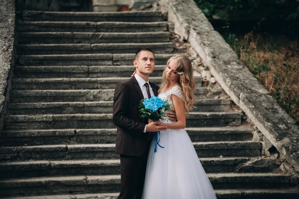 Luxus-Hochzeitspaar umarmt und lächelt einander auf der Treppe im Schloss — Stockfoto