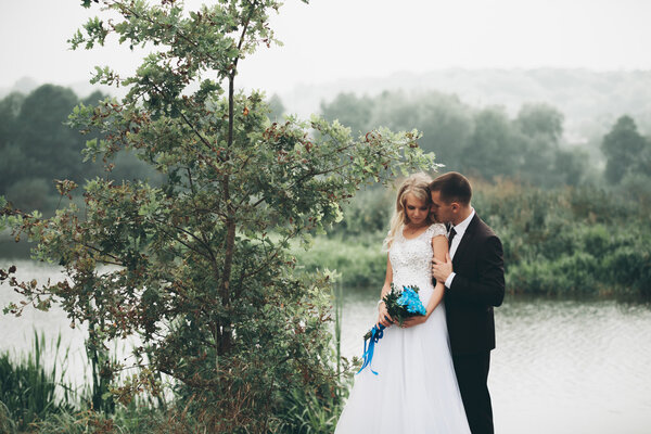 Romantic wedding couple, man and wife, posing near beautiful lake