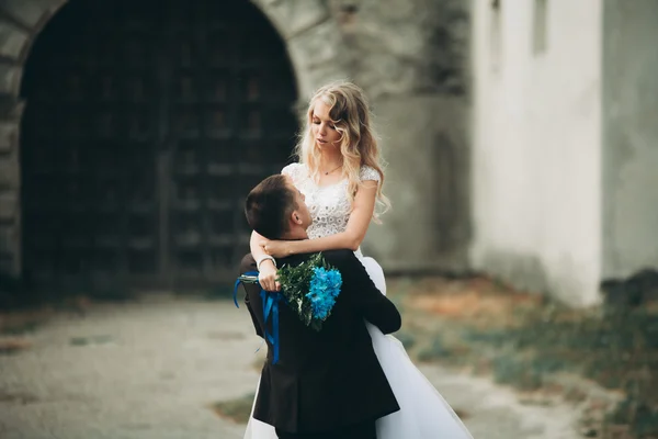 Glückliches Hochzeitspaar umarmt und küsst sich auf alter Burg — Stockfoto