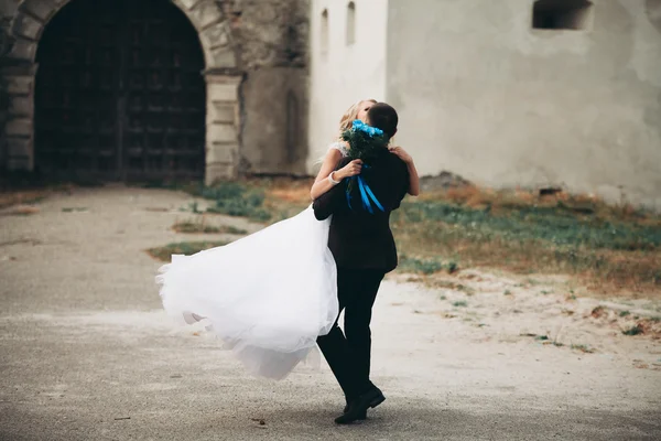 Verheugd huwelijksfeest paar knuffelen en zoenen op achtergrond oud kasteel — Stockfoto