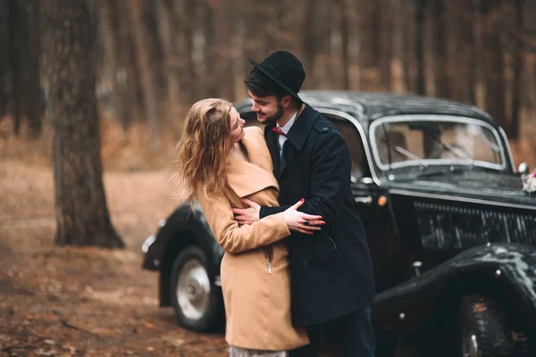 Elegante coppia di nozze amorevole baciare e abbracciare in una pineta vicino auto retrò — Foto Stock