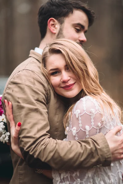 Stylish Loving wedding couple kissing and hugging in a pine forest near retro car — Stock Photo, Image