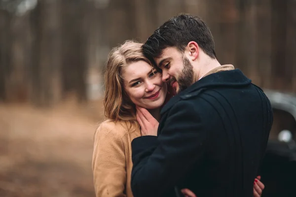 Stylish Loving wedding couple kissing and hugging in a pine forest near retro car — Stock Photo, Image