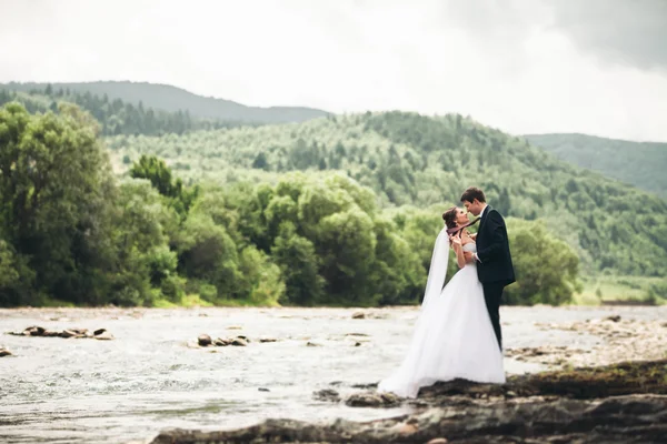 Elegáns, finom, elegáns vőlegény és a menyasszony kövekkel-folyó közelében. Esküvő a pár a szerelem — Stock Fotó