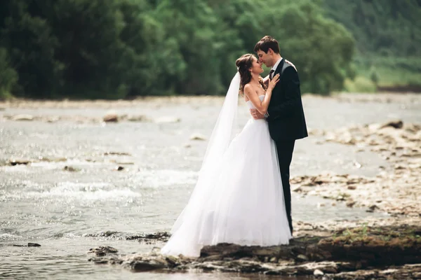 Zarif nazik şık damat ve gelin taşlarla Nehri yakınında. Evlilik çift aşık