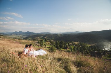 Güzel düğün çifti ile meyve ve pasta Dağları'nın bir arka plan üzerinde piknik
