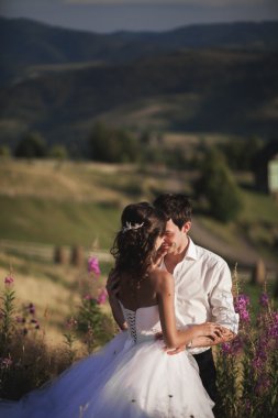 Öpüşme ve dağlar bir arka plan üzerinde kucaklayan romantik peri masalı çift yeni evliler