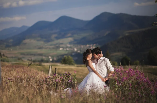 Romántica pareja de cuentos de hadas recién casados besándose y abrazándose en un fondo de montañas —  Fotos de Stock